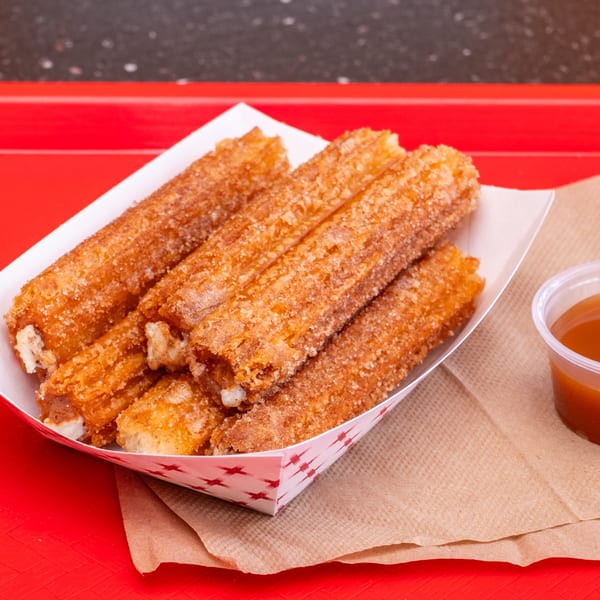 Chili Hots' cinnamon sugar churros in a paper tray with a side of caramel dipping sauce.